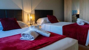 A hotel room with two beds, each with a red blanket and white pillows. There are two bedside tables with lamps. - Casa Rural en Cardona (Cardona)