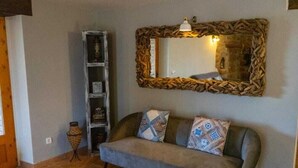 A living room with a grey sofa, patterned cushions, a wooden-framed mirror, and a tall bookshelf. - Casa Rural en Cardona (Cardona)
