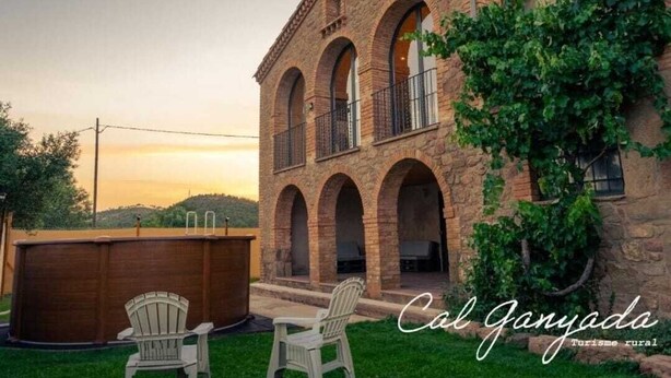 A stone building with arched windows and a balcony, surrounded by greenery. - Casa Rural en Cardona (Cardona)