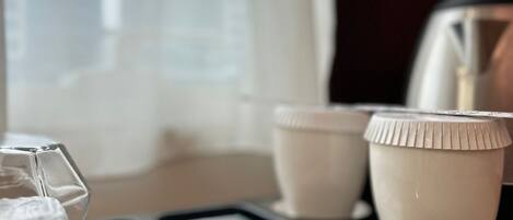 Una bandeja con un vaso de agua, dos tazas blancas y una revista.