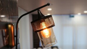 Uma sala de jantar com mesas preparadas para o serviço, um lustre e uma parede de mármore.