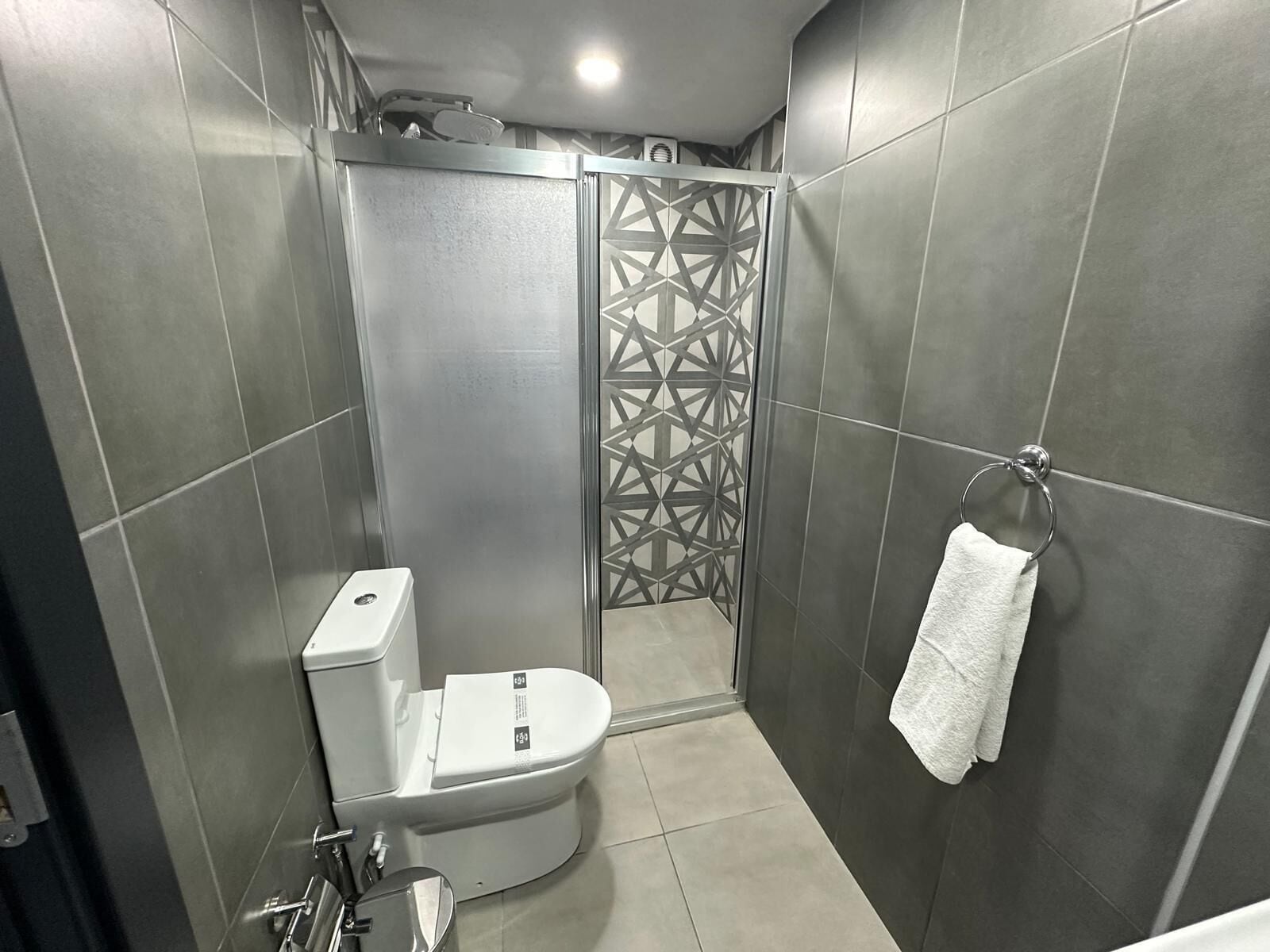 A modern bathroom with a toilet, shower, and towel rack.
