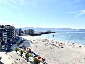 A beach with a road and buildings in the background.