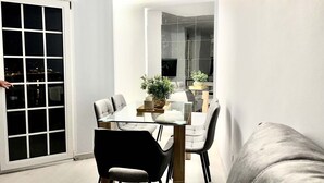 Ett modernt matområde med ett glasbord, fyra stolar och en krukväxt.