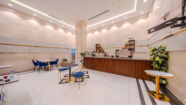 A modern hotel lobby with a reception desk, seating area, and a large potted plant. - Al Marzam Hotel (Madinah)