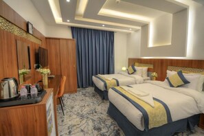 Una habitación de hotel con dos camas, un escritorio con hervidor y un televisor.