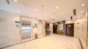 A spacious lobby with a marble floor, an elevator, a staircase, and a reception area. - Al Marzam Hotel (Madinah)