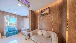 A modern hotel lobby with a beige sofa, a blue armchair, a small table, and a framed picture on the wall. - Al Marzam Hotel (Madinah)