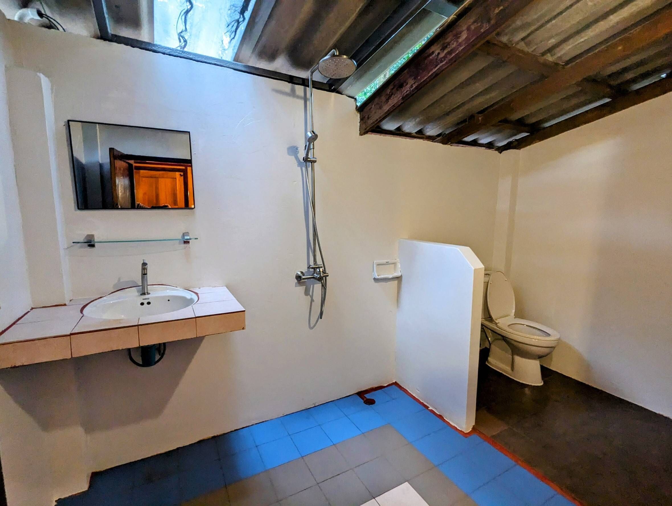A bathroom with a sink, mirror, shower, and toilet.