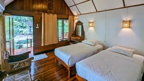 A cozy room with wooden walls and a sloped ceiling, featuring two beds, a wooden bench, and a small table. - Ziggy Stardust (Ranong)