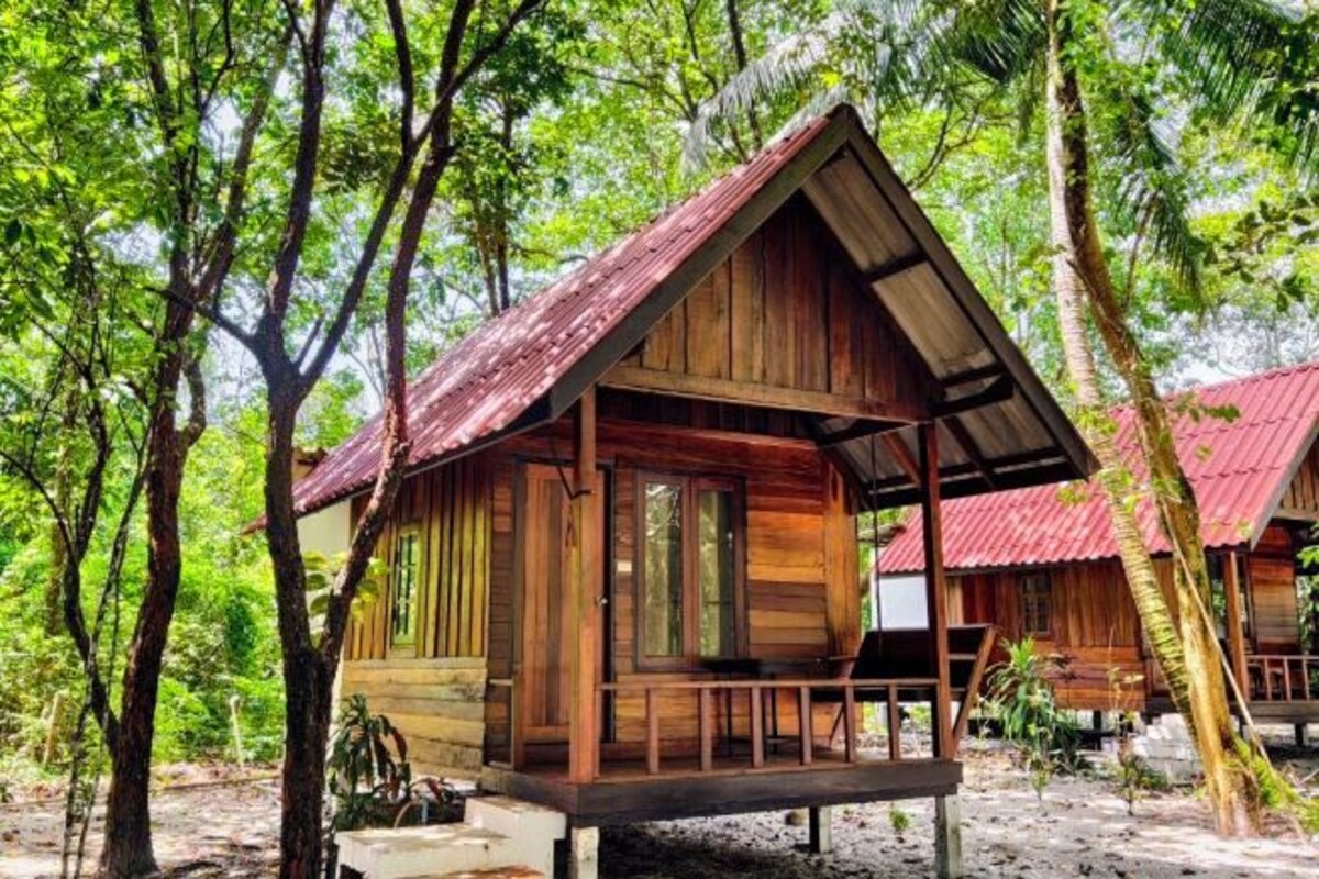 A wooden cabin with a sloped roof, surrounded by trees.