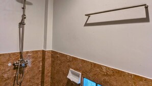 A shower with a handheld showerhead, a towel rack, and a small trash bin. - Ziggy Stardust (Ranong)