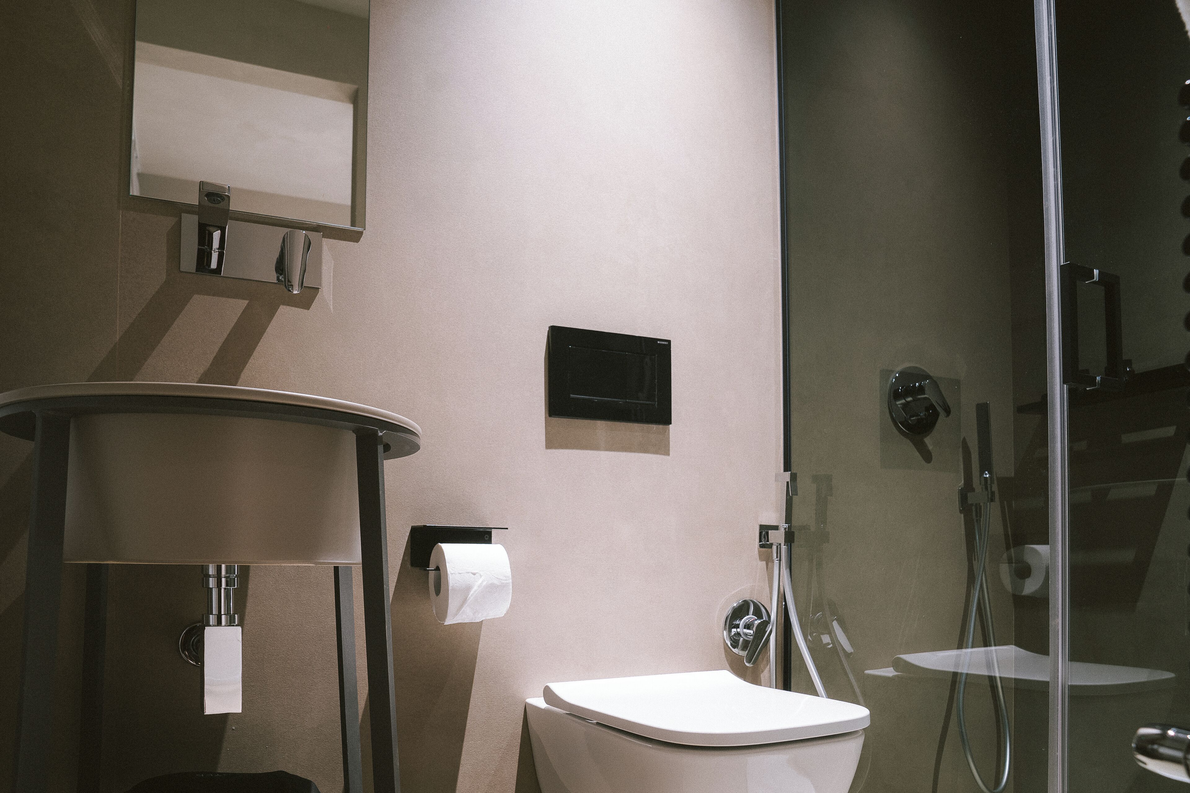 A modern bathroom with a toilet, a sink, a mirror, and a shower.
