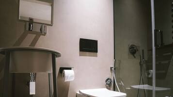 Une salle de bain moderne équipée d’un WC, d’un lavabo, d’un miroir et d’une douche.