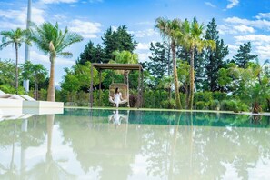 A serene pool area with a swing chair, lush greenery, and a clear sky. - Villa Grumolara & Spa (Lamezia Terme)