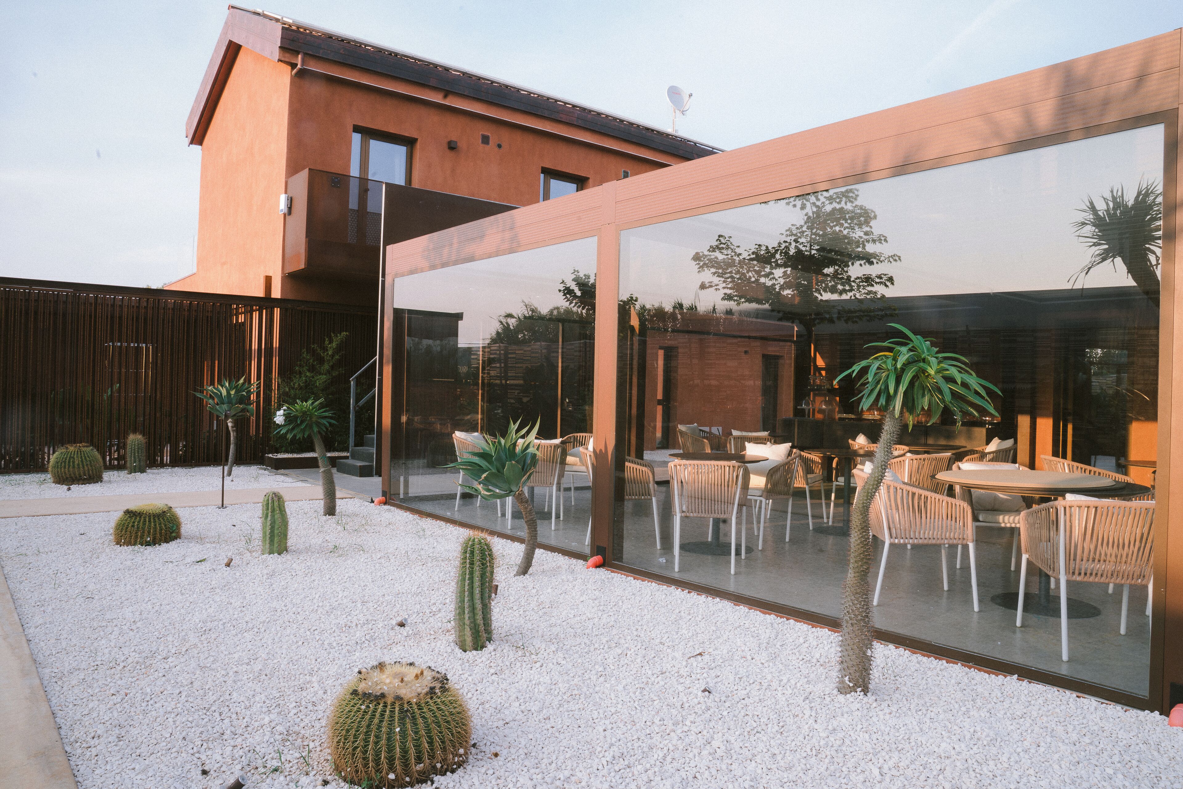 Une terrasse extérieure moderne, agrémentée de gravier blanc, de cactus et de meubles en osier.
