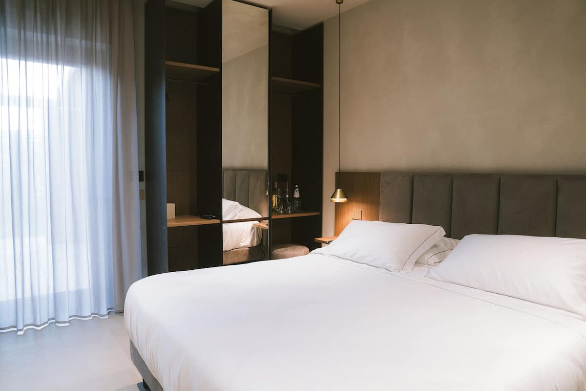 Een moderne hotelkamer met een groot bed, een nachtkastje, een spiegel en een kledingkast.