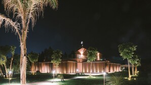 A modern building with a dome and a weather station on top, surrounded by well-lit pathways and greenery. - Villa Grumolara & Spa (Lamezia Terme)