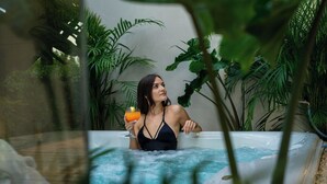 A woman in a black swimsuit sitting in a hot tub surrounded by lush green plants. - Villa Grumolara & Spa (Lamezia Terme)