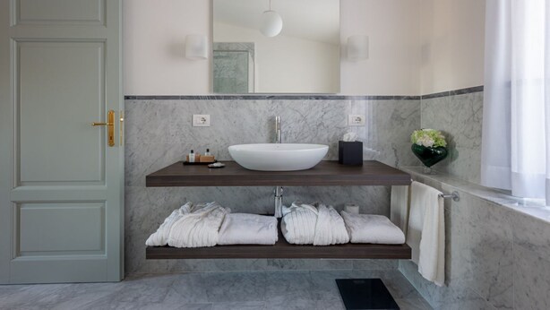 A bathroom with a white sink, marble countertop, and a towel rack.