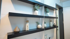 Un baño con estantes negros que exhiben adornos y plantas.