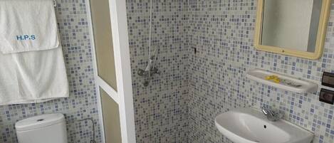 Un baño con ducha azulejada, lavamanos y retrete.