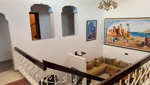 Una escalera con barandales blancos ornamentados y un suelo de alfombra roja con estampado.