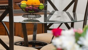 A dining area with a glass table, metal fruit basket, and dark wooden chairs. - * Central London Haven With AC. Steps To Big Ben * (Greater London)