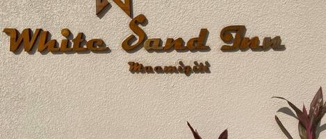 A sign for White Sand Inn with a logo and name in wooden letters.