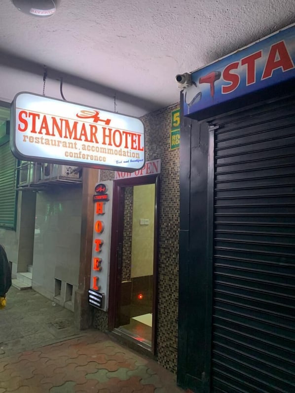 Entrada de un hotel con un letrero que dice "STANMAR HOTEL" y "ABIERTO AHORA".