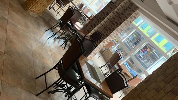 Um restaurante com paredes de tijolo, chão de azulejos e vista para a rua.
