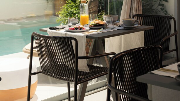 Un área de comedor con una mesa lista para el desayuno, con vista a una piscina.