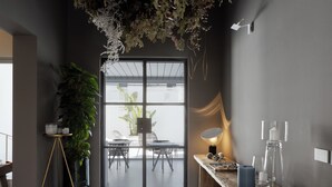 Un interior moderno con un arreglo de plantas colgantes, un banco de madera y una mesa de vidrio con una lámpara.