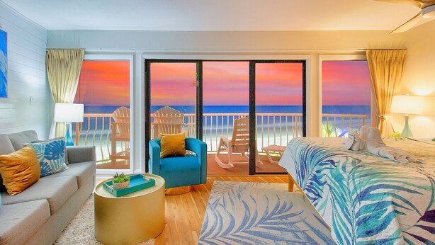 A hotel room with a balcony, a sofa, a chair, a bed, and a small table. - Huge 25 foot circle balcony/MODERN COASTAL/Best view in Myrtle Beach (Myrtle Beach)