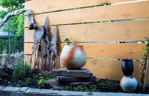 A garden with a wooden bench, a large ceramic pot, and a smaller vase.