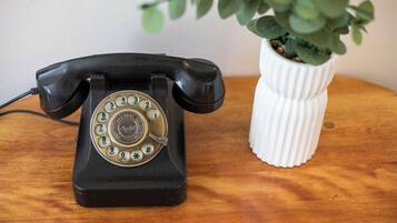 Un telefono da tavolo vintage nero con tastiera rotativa su un piano di legno.