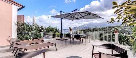 A terrace with outdoor furniture, a table, and a large umbrella.