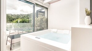 Ein modernes Badezimmer mit einer großzügigen Badewanne, einer gläsernen Dusche und Blick auf eine üppige grüne Landschaft.