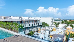 A hotel with a rooftop pool, multiple balconies, and a view of the surrounding cityscape. - Anah 410 2 Bedroom Condo by RedAwning (Playa del Carmen)