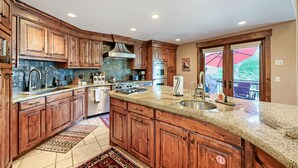 A kitchen with wooden cabinets, granite countertops, stainless steel appliances, and a view to the outside. - 2430 Deer Valley Getaway! Peaceful Home Minutes From Deer Valley With Private Hot Tub! 4 Bedroom Home by RedAwning (Park City)