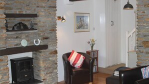 A cozy living room with a stone fireplace, a leather armchair, and a bookshelf.