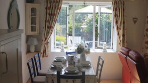 A dining area with a table set for four, a red sofa, and a window with curtains.