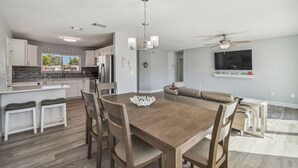 Una cocina moderna con armarios blancos, una mesa de comedor de madera y una araña.