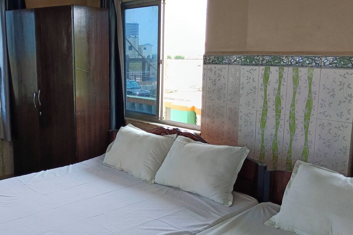 Habitación de hotel con cama, armario, ventana con cortinas y vistas al exterior.