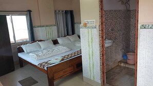 Un dormitorio con cama de madera, ventana con cortinas, baño con ducha y suelo de baldosas.