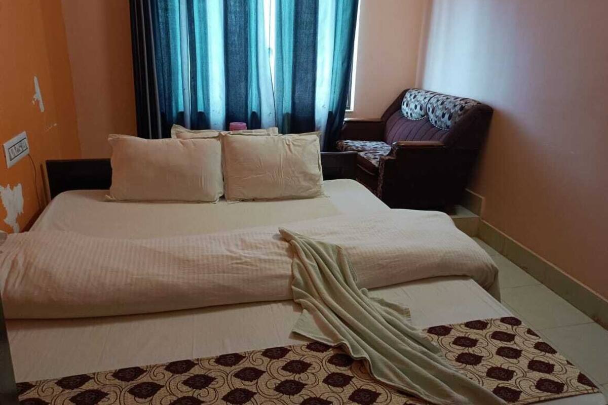 Una habitación de hotel con cama, una silla y ventana con cortinas.