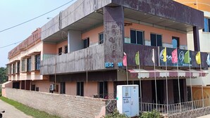 Un edificio de varios pisos con balcones, un cartel y un área cercada con banderas de colores.