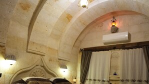 A cozy, arched room with a large bed, two bedside lamps, and a radiator. - Cevizli Konak (Nevsehir)