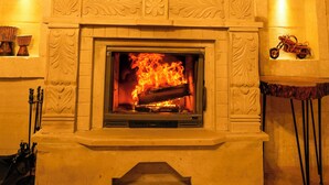 A fireplace with intricate carvings, a mantel with decorative items, and a small shelf with a motorcycle. - Cevizli Konak (Nevsehir)