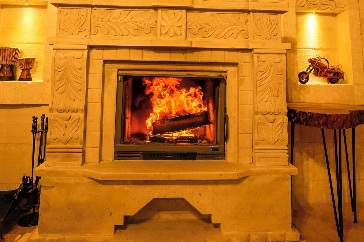 A fireplace with intricate carvings, a mantel with decorative items, and a small shelf with a motorcycle.